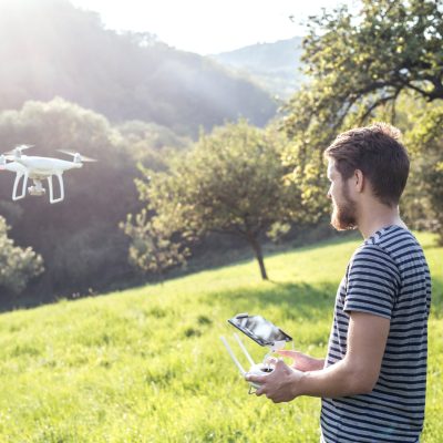 young hipster man with flying drone. sunny green nature.